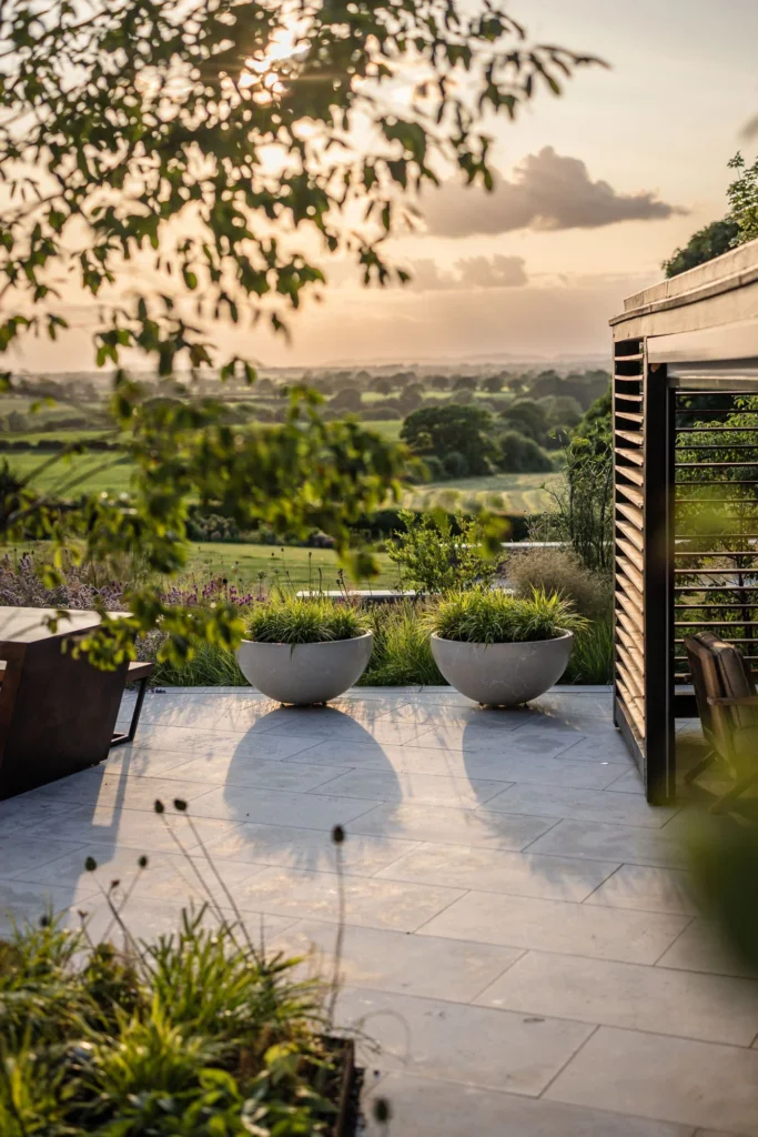 Modern terrace with round planters and sunset views over rolling countryside.